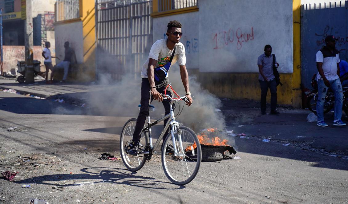
En man cyklar förbi ett brinnande däck i Haitis huvudstad Port-au-Prince den 2 september 2022. Landet plågas av hög kriminalitet, matbrist och fattigdom. Foto: Richard Pierrin/AFP via Getty Images                                            