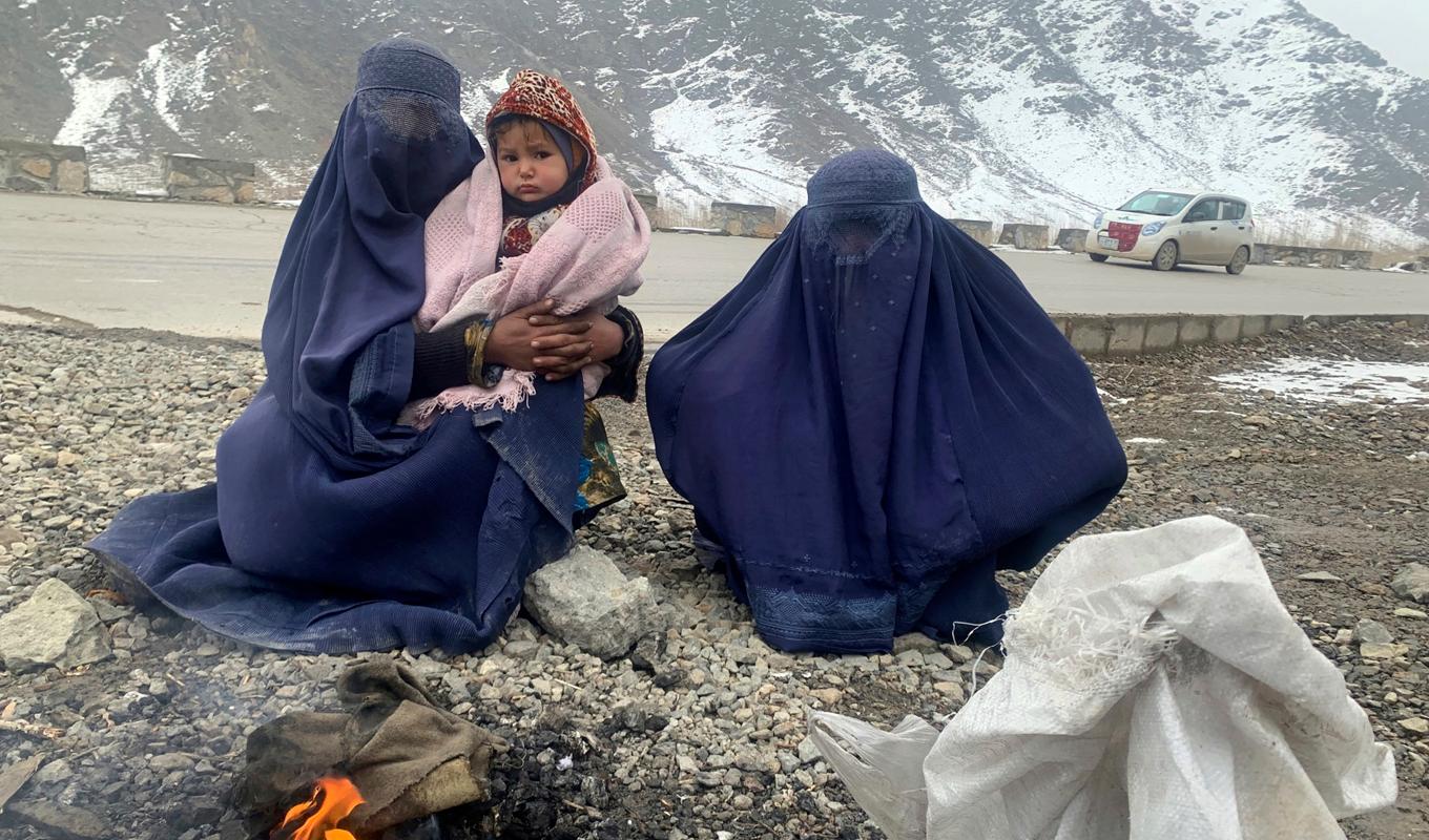 Två kvinnor och en 1,5 år gammal pojke värmer sig vid en brasa i östra Afghanistan i januari 2022. Foto: Kathy Gannon/AP/TT