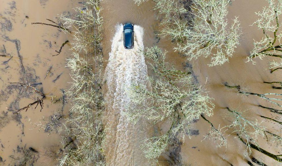 En bil kör på en översvämmad väg i Sebastopol, Kalifornien, den 5 januari. En rad vinterstormar drar in över USA:s västra kust med kraftigt regn, tung snö och jordskred. Det får guvernör Gavin Newsom att utlysa undantagstillstånd. Foto: Josh Edelson/AFP via Getty Images