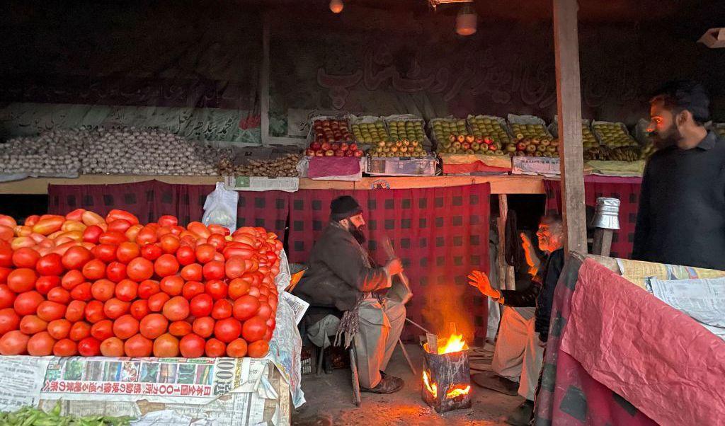Handlare på en marknad i Muzaffarabad värmer sig vid en brasa under ett rikstäckande strömavbrott i Pakistan den 23 januari. Elavbrottet drabbade de flesta av landets mer än 220 miljoner människor. Foto: Sajjad Qayyum/AFP via Getty Images
