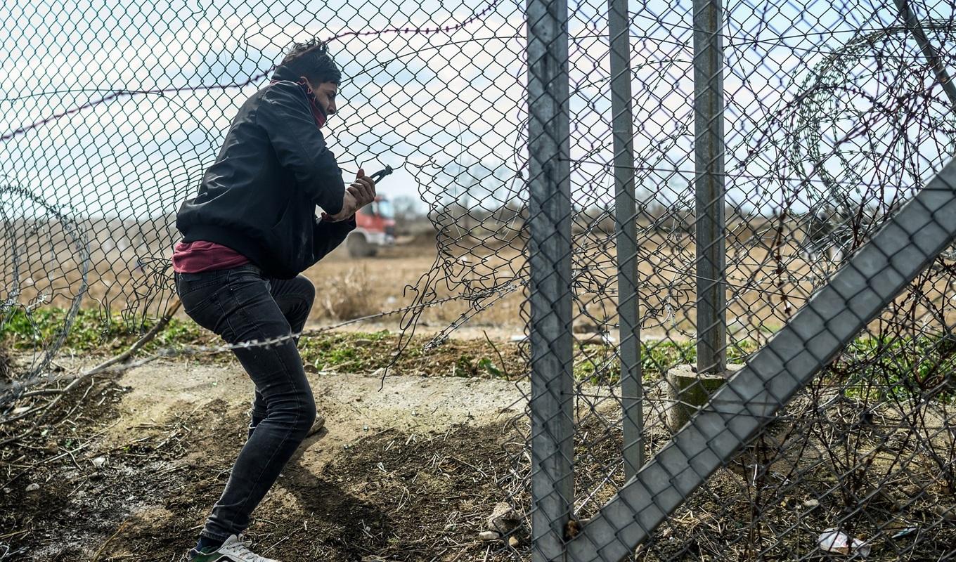 En migrant klipper upp ett stängsel vid den turkisk-grekiska gränsen den 7 mars 2020. Foto: Bulent Kilic(AFP via Getty Images