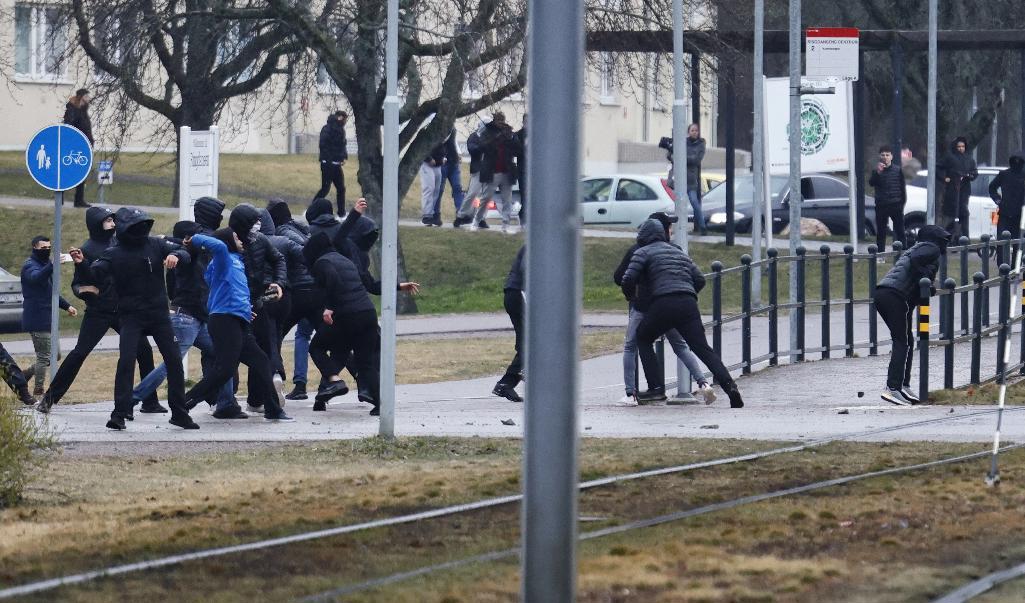 Personer, flera av dem maskerade, kastar stenar mot blåljuspersonalen under påskupploppen i stadsdelen Navestad i Norrköping. Foto: Stefan Jerrevång/TT