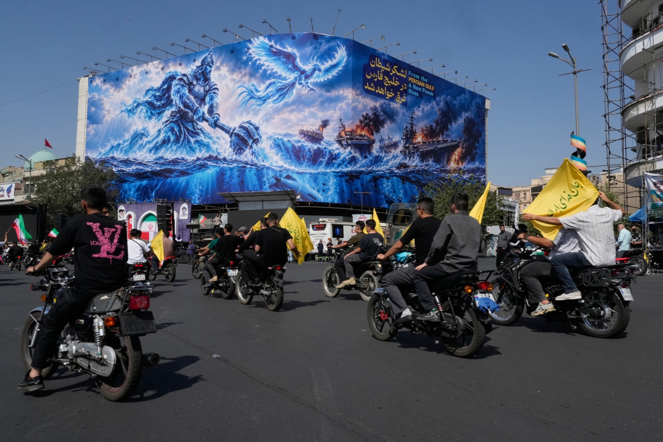 Motorcyklister i Teheran passerar en stor propagandatavla, som hyllar iranska angrepp mot fartyg: ”Satans armé kommer att dränkas i Persiska viken”. Bilden togs den 25 september. Foto: Vahid Salemi/AP/TT
