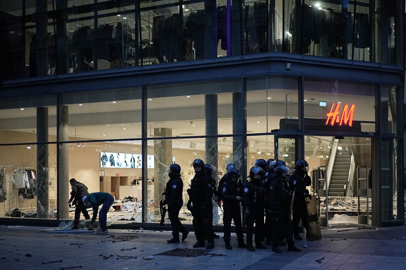 Poliser vid en delvis sönderslagen H&M-butik i Lyon den gångna helgen. Foto: Laurent Cipriani/AP/TT