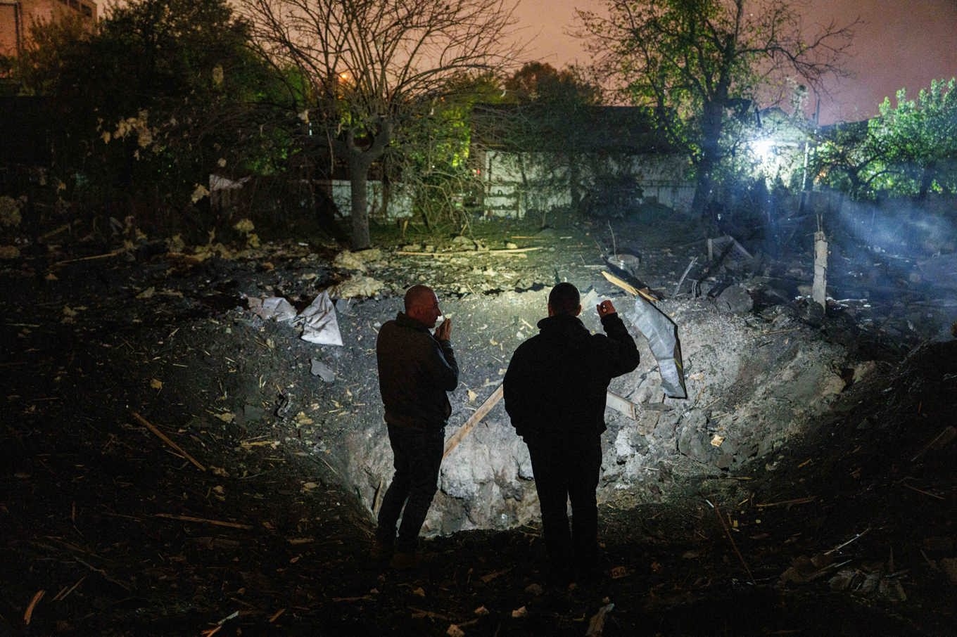 Två män vid en krater där en rysk projektil slagit ner i Kiev på onsdagen. Foto: Evgeniy Maloletka/AP/TT
